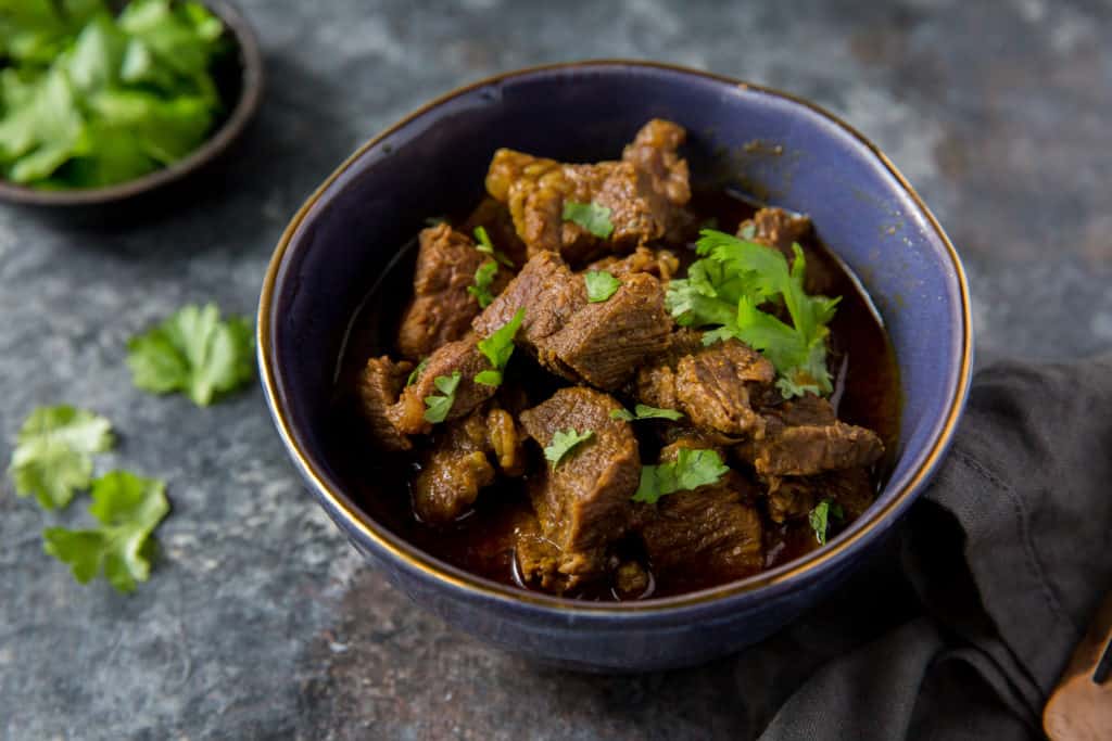 beef curry beef curry served in a blue bowl with a garnish of cilantro
