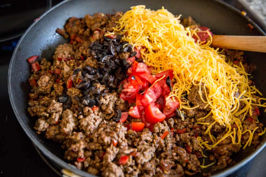 Keto Taco Salad ground beef, olives, tomatoes and cheese cooked in a skillet for a keto taco salad casserole