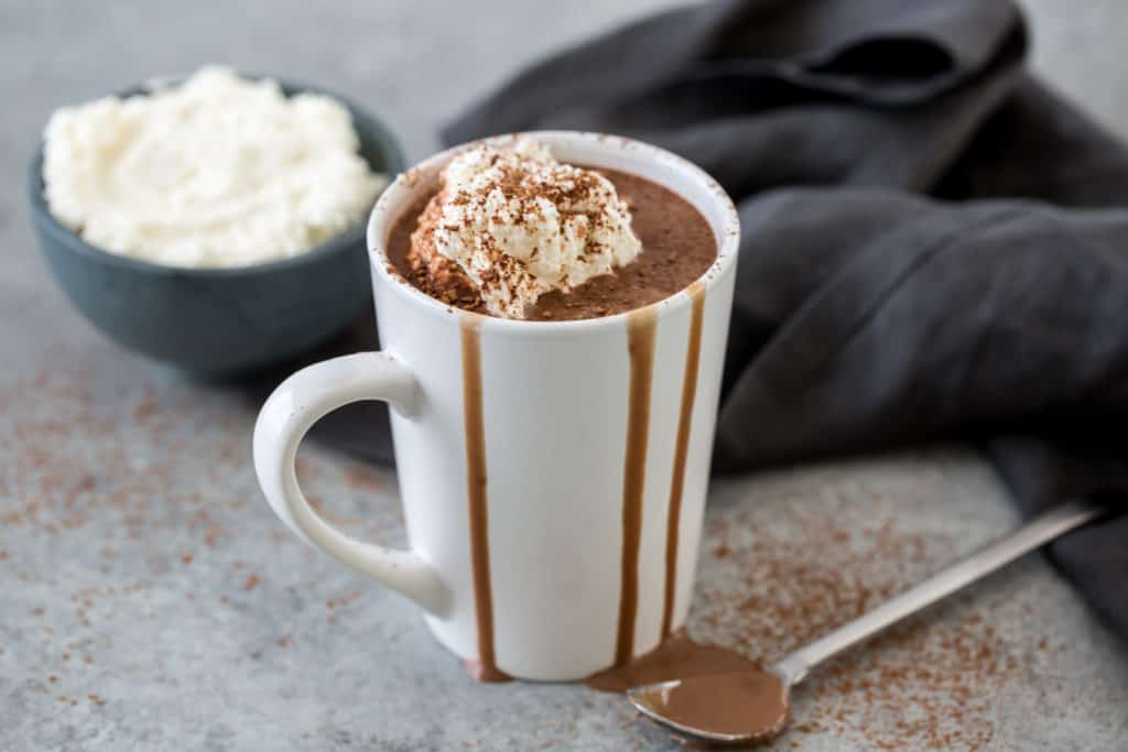 keto hot chocolate in a white mug topped with sugar free whip cream and cocoa powder