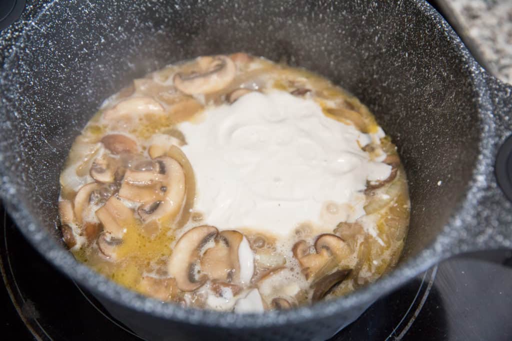 Keto Beef Stroganoff keto beef stroganoff cooking in a skillet with sour cream, mushrooms, onions and beef broth