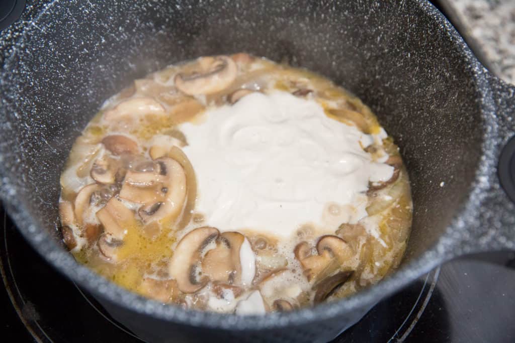 keto beef stroganoff cooking in a skillet with sour cream, mushrooms, onions and beef broth