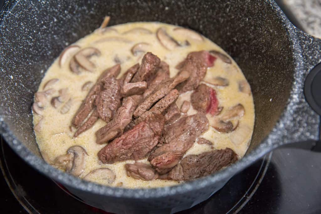 Keto Beef Stroganoff keto beef stroganoff cooking in a skillet with a cream sauce and sliced ribeye steak