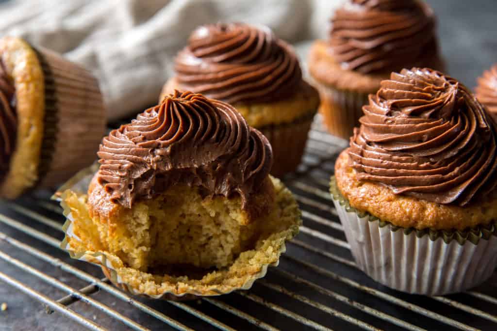 chocolate frosted keto cupcakes in paper muffin liners on a cooling rack 