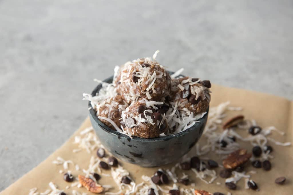 Keto Energy Balls keto energy balls rolled in coconut flakes served in a bowl on parchment paper