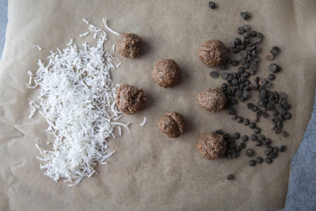Keto Energy Balls keto energy balls on parchment paper with coconut flakes and low carb chocolate chips