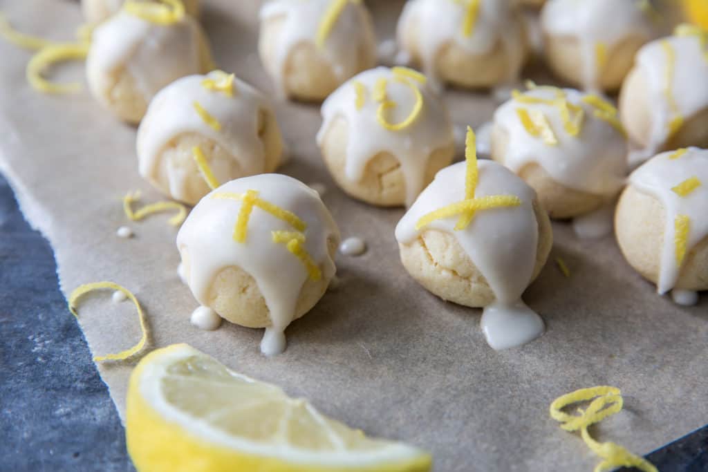 baked keto lemon cookies topped with a lemon glaze and lemon zest garnish on parchment paper
