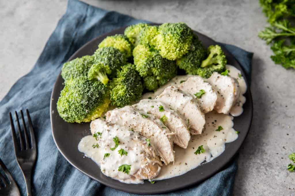 instant pot creamy chicken sliced and served on a black plate with broccoli 