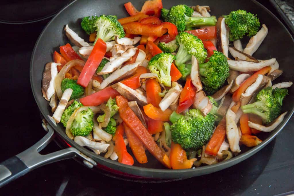 keto chicken stir fry vegetables being cooked in a cast iron skillet prior to adding chicken