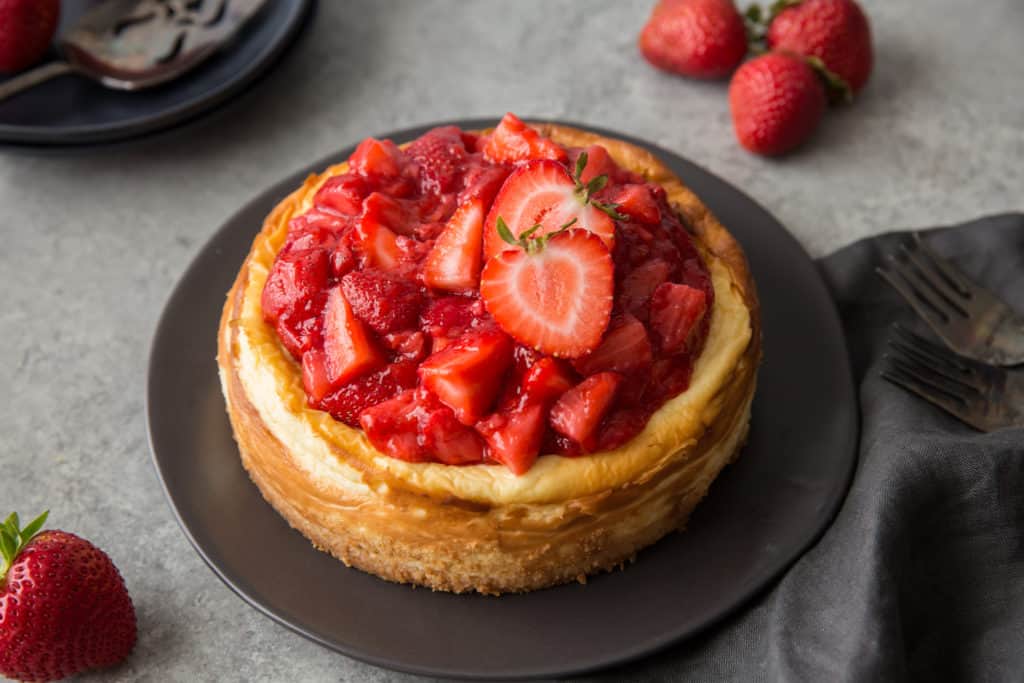 a keto strawberry cheesecake served on a black plate with strawberry garnish