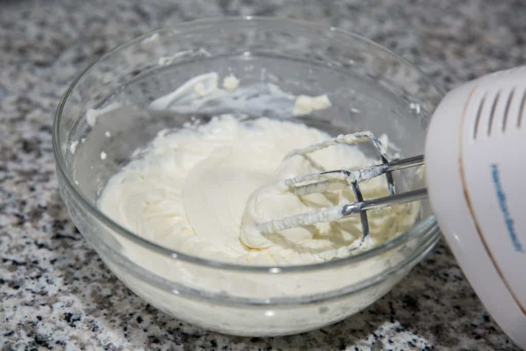 keto strawberry cheesecake filling in a mixing bowl with a hand mixer