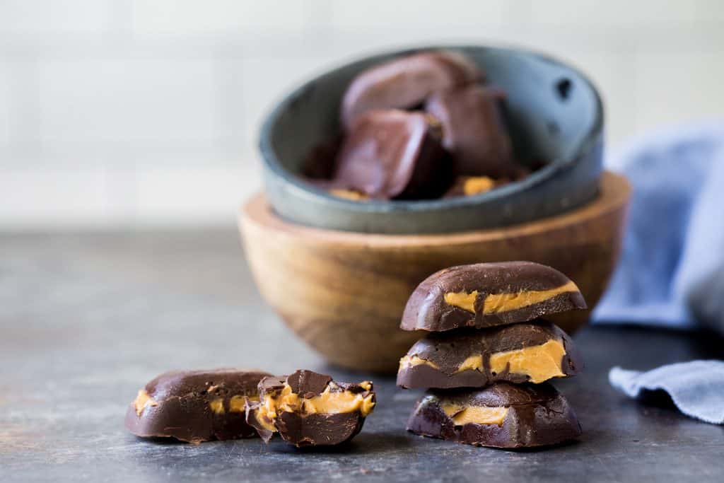 keto peanut butter cups stack of cups with one broken in front of a bowl