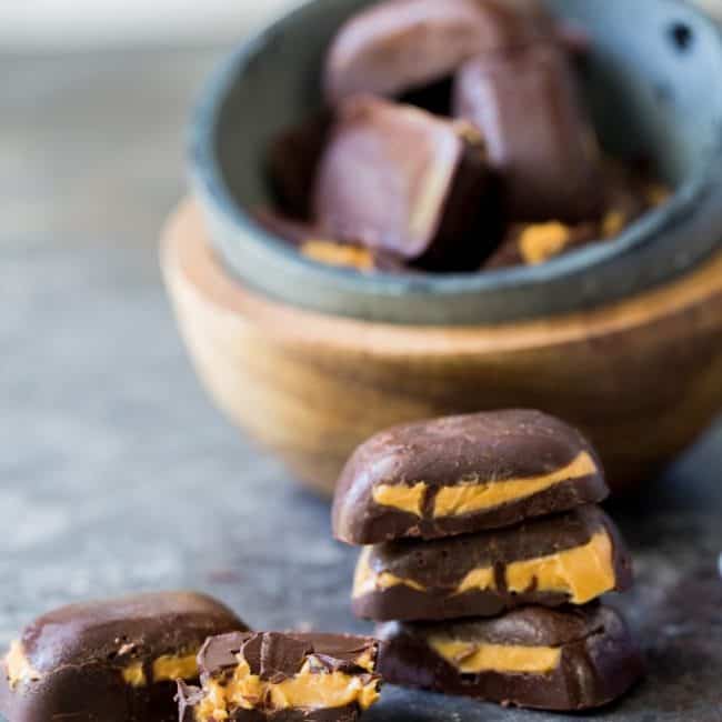 keto peanut butter cups stack of cups in front of a full recipe in a bowl