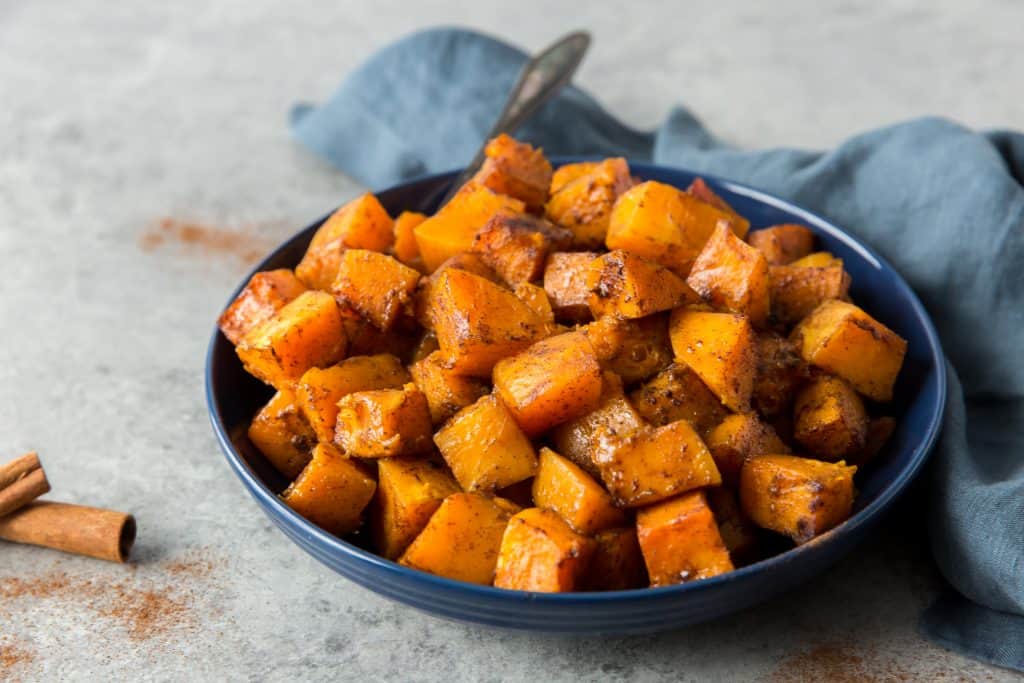 butternut squash dished up next to a bright blue cloth and cinnamon stick