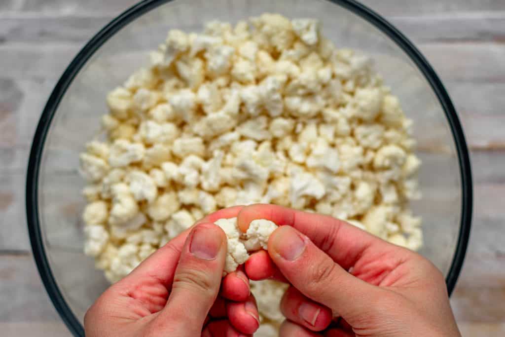 Cauliflower Mac and Cheese Hands carefully breaking cauliflower into noodle sized pieces