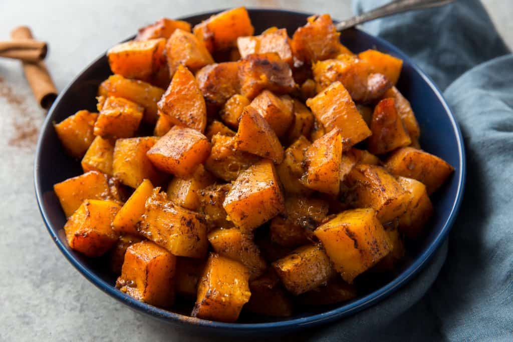 Finished butternut squash ready to serve in a blue bowl with a silver spoon