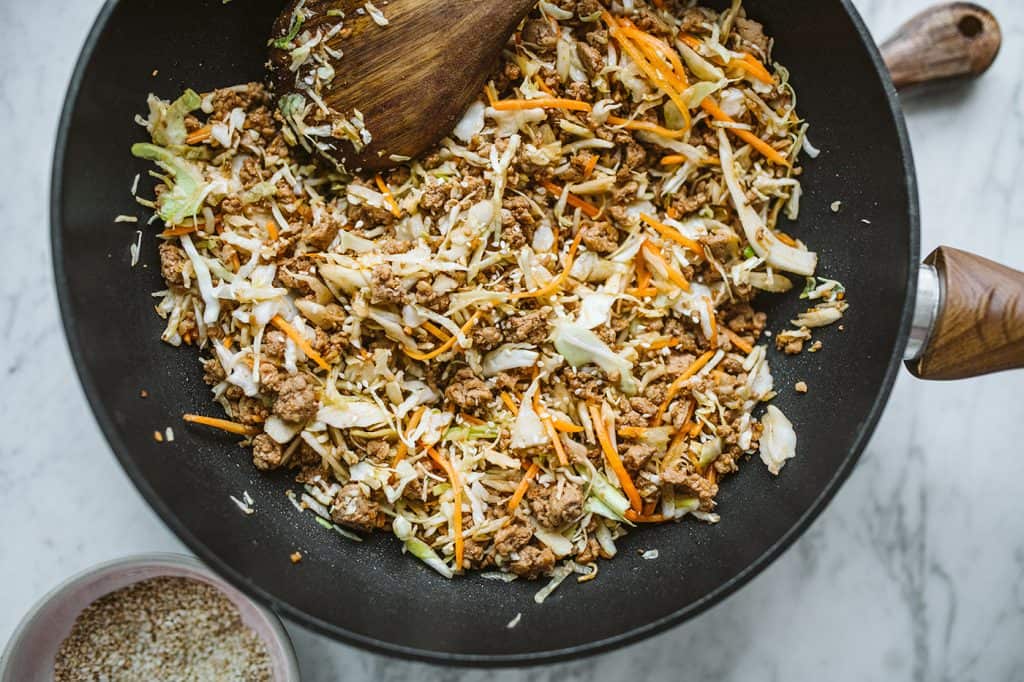 Keto Egg Roll In A Bowl Completed recipe inside a black pan with a wooden spoon to serve