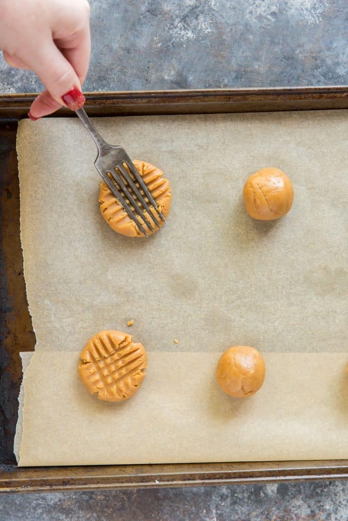 Cookie dough being pressed with a silver fork.