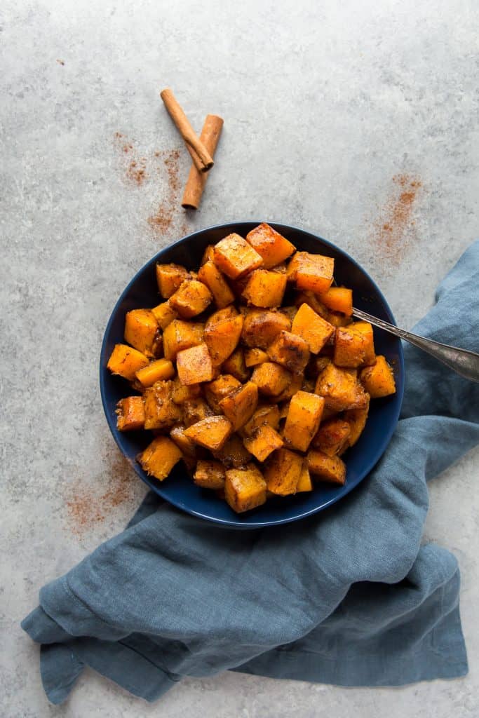 butternut squash keto A serving dish next to fresh cinnamon and a cinnamon stick