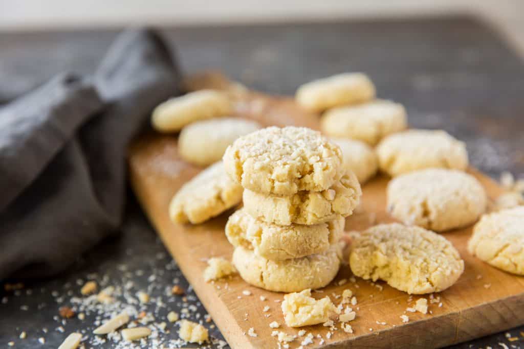 Keto cookies stacked on a cutting board next to a cooking cloth