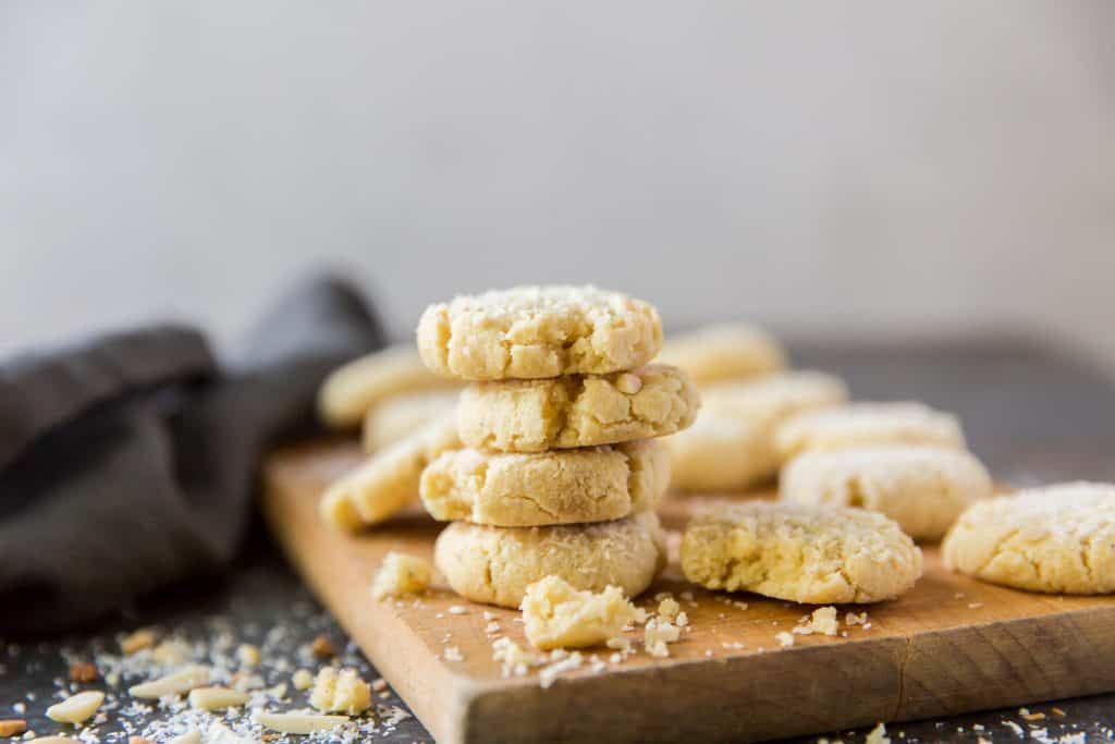 Keto Oatmeal Cookies A wood cutting board with oatmeal cookies stacked on top