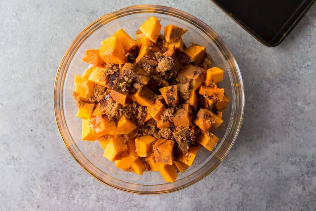 Coating the squash with brown sugar, cinnamon, salt, and oil