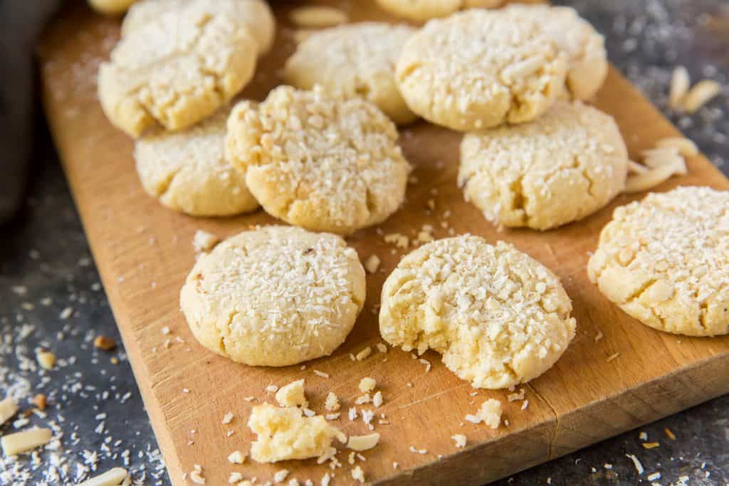 Oatmeal cookies on a cutting board, surrounded by coconut flakes