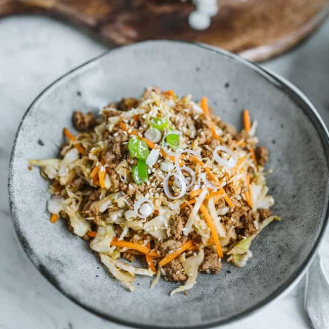 Keto Egg Roll In A Bowl egg roll in a bowl served on a plate with cutting board in the background