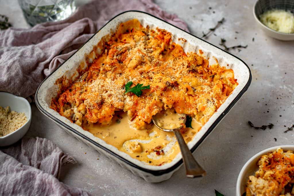 Cauliflower Mac and Cheese serving dish on a dinner table with many bowls around it