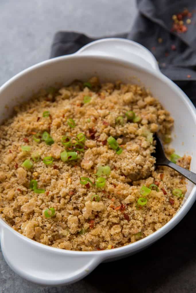 Tuna casserole being served with a black metal spoon 