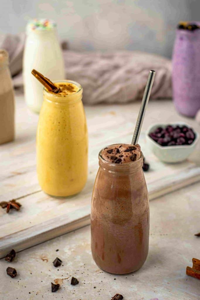 Keto shakes surrounded by toppings and chocolate pieces