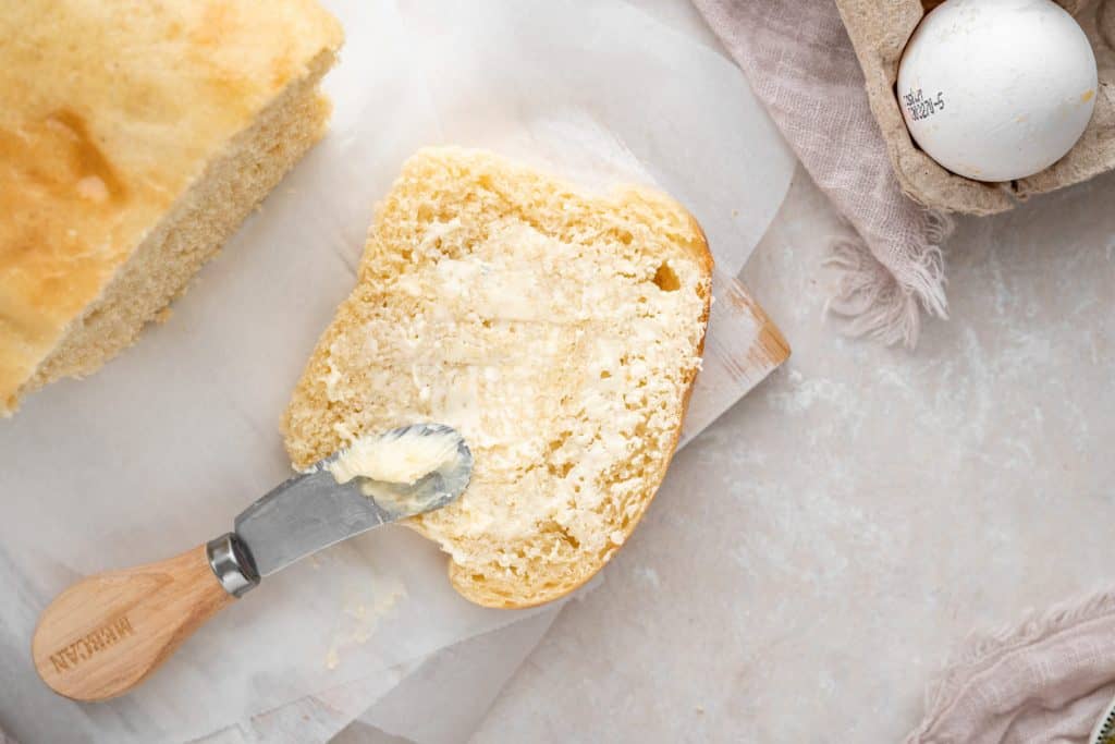 A small cheese knife buttering bread 