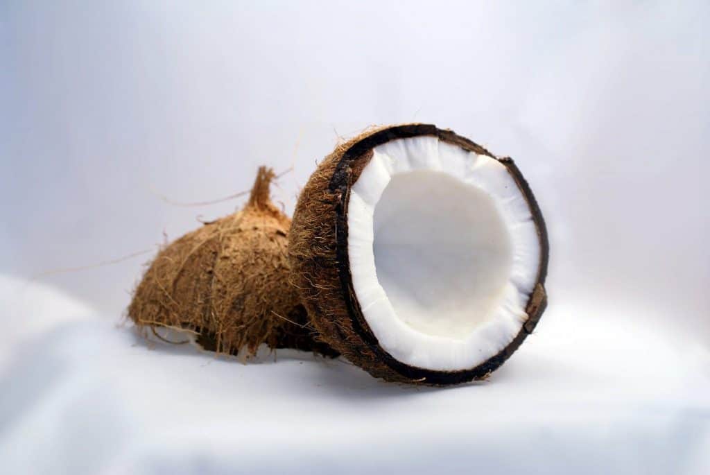 a coconut broken in half on top of sand