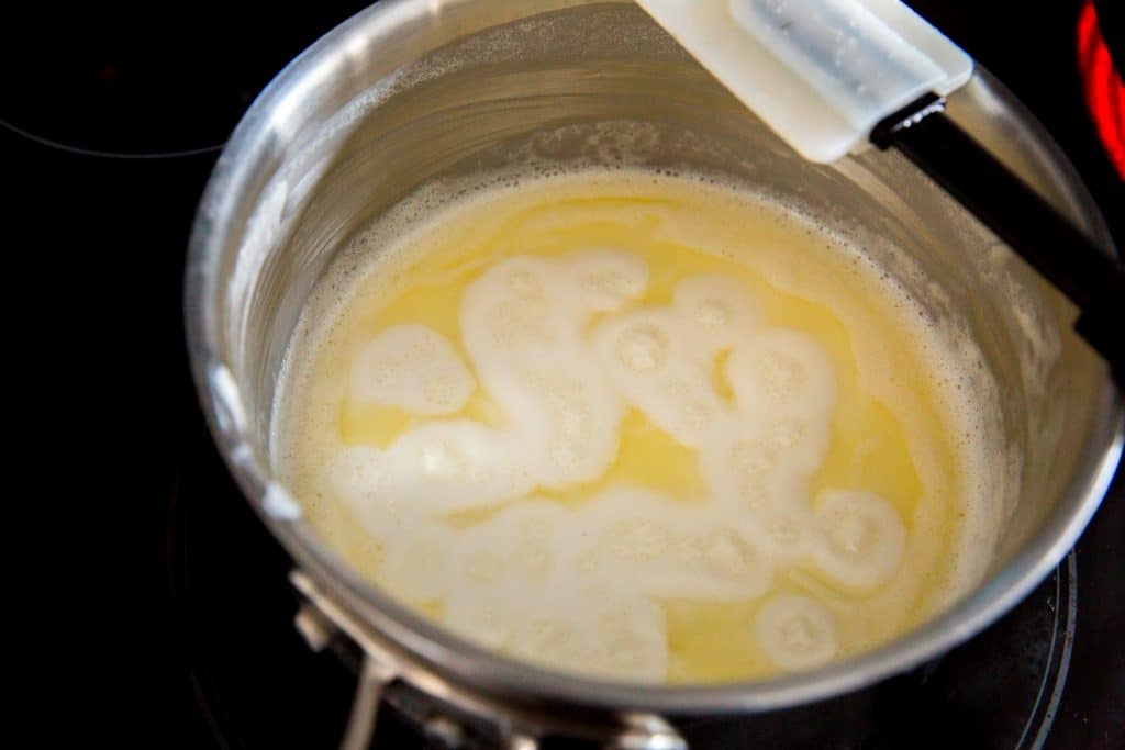 A saucepot simmering on the stove with a spatula across the center. 