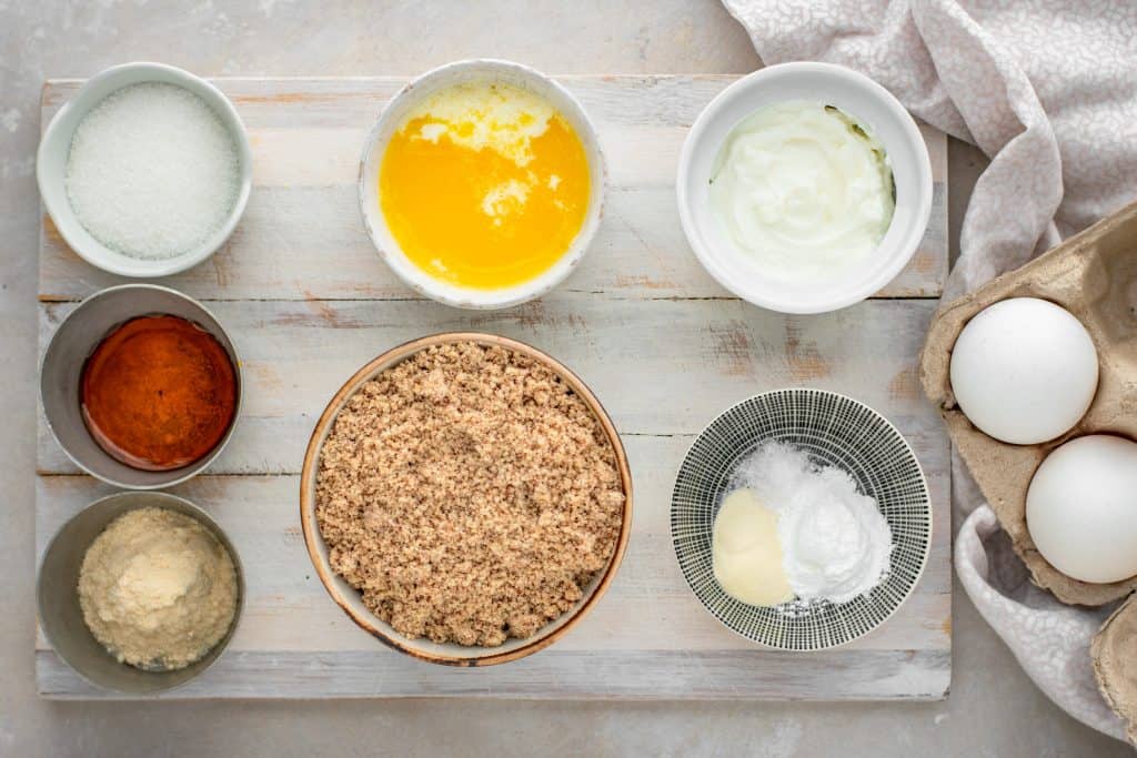 Bowls of ingredients to make keto waffles on a wooden cutting board