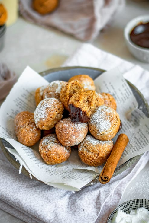 Keto donuts on a blue plate next to a cinnamon stick. 