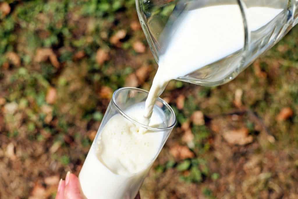 milk being poured into a glass from a pitcher