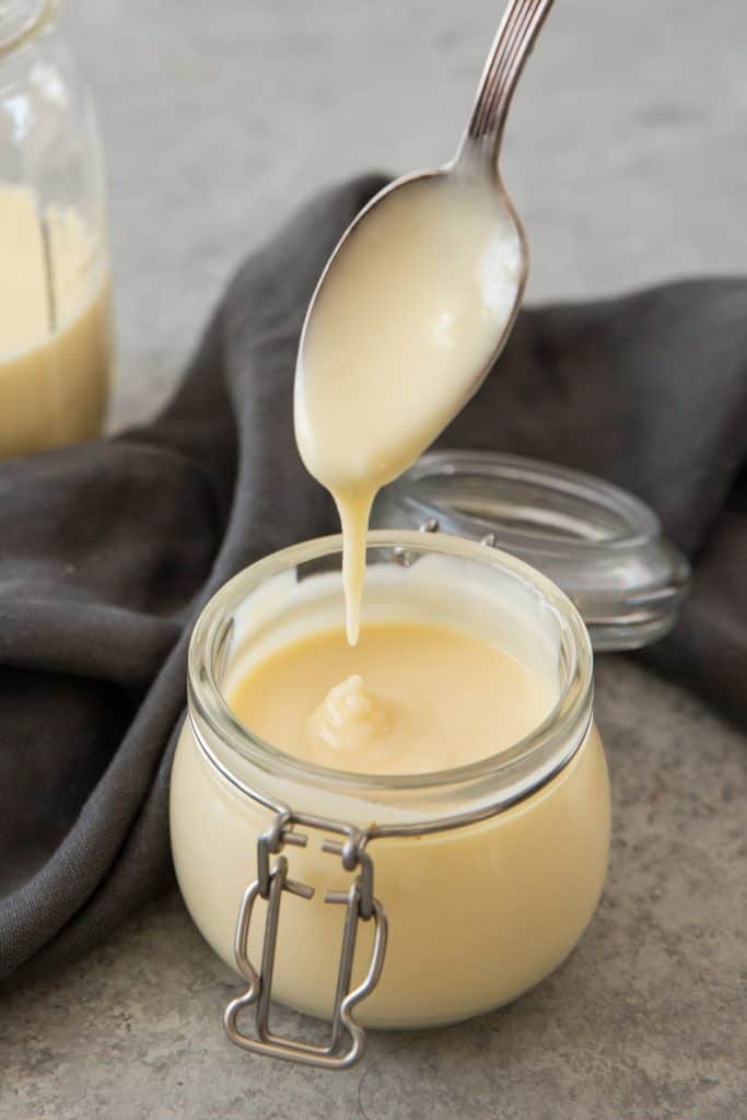 A silver spoon dipped into the finished, thick, condensed milk