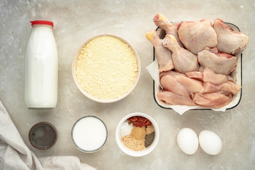 Keto Fried Chicken Chicken, spices, and ingredients for a marinade on a marble countertop