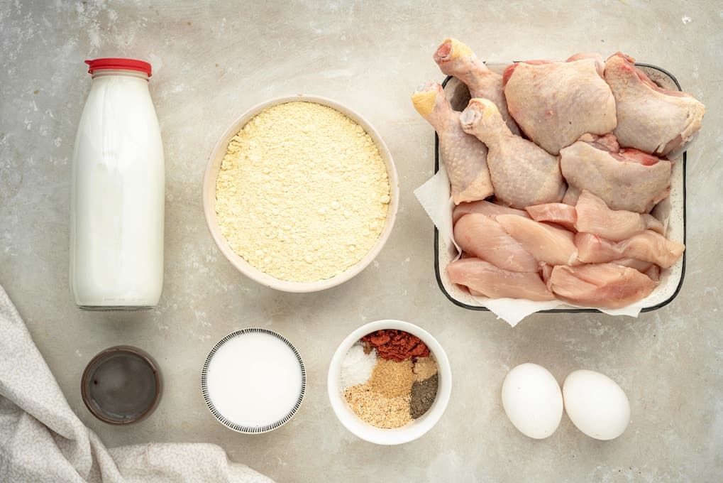 Chicken, spices, and ingredients for a marinade on a marble countertop