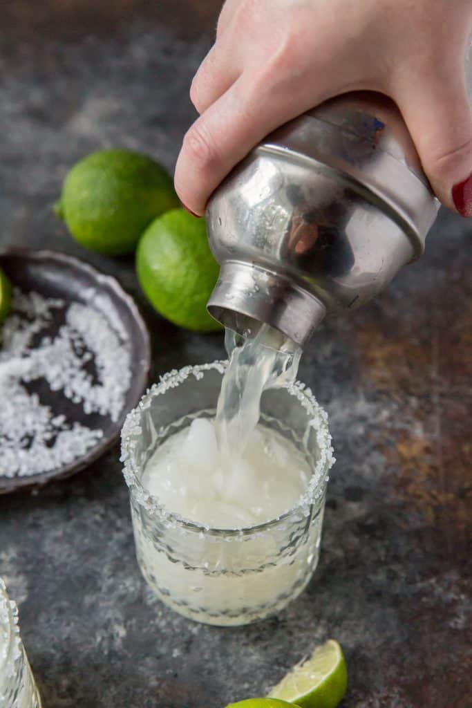 A margarita being poured from a silver cocktail shaker. 