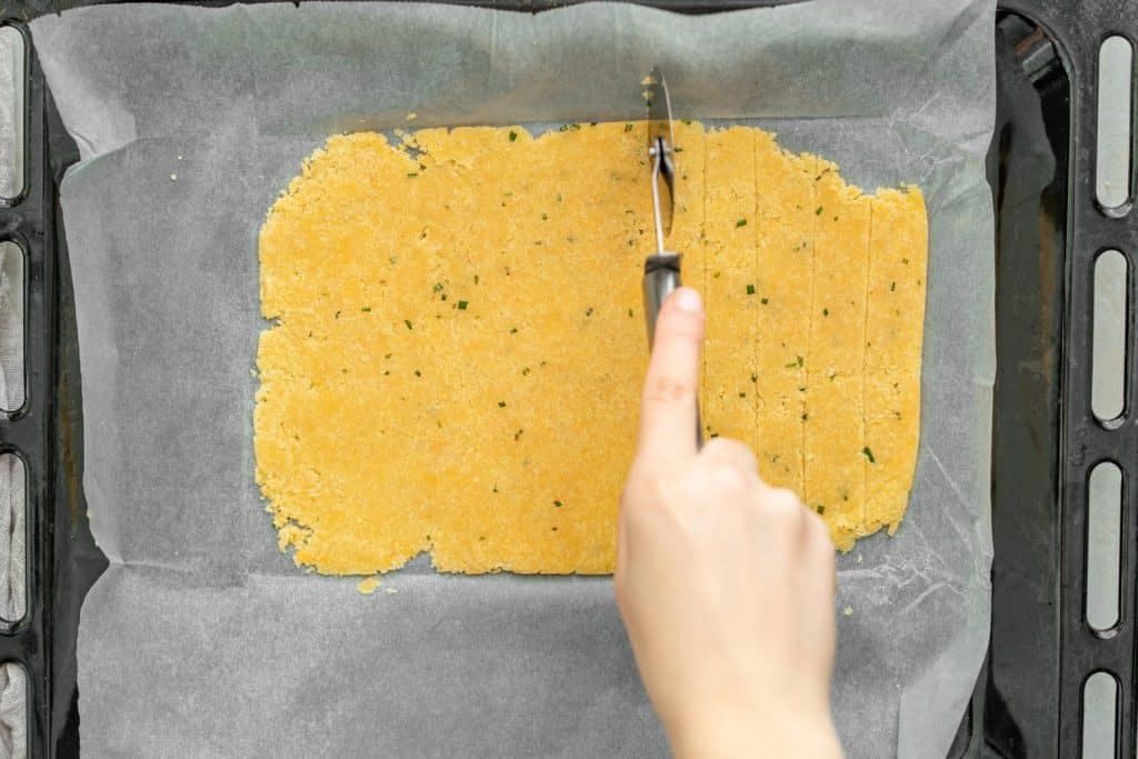 Keto Crackers Cutting crackers on a baking sheet and parchment paper