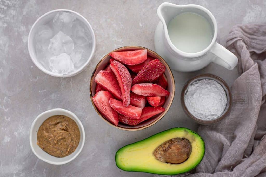 almond butter avocado and sliced strawberries are ingredients for a strawberry keto smoothie