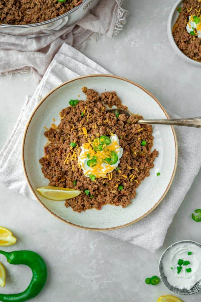 A single lemon wedge next to a plate of keto chili