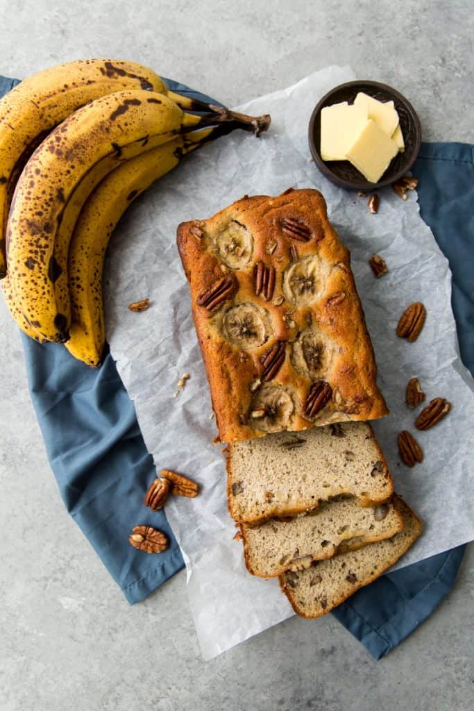 sliced banana bread on top of parchment paper with pecans