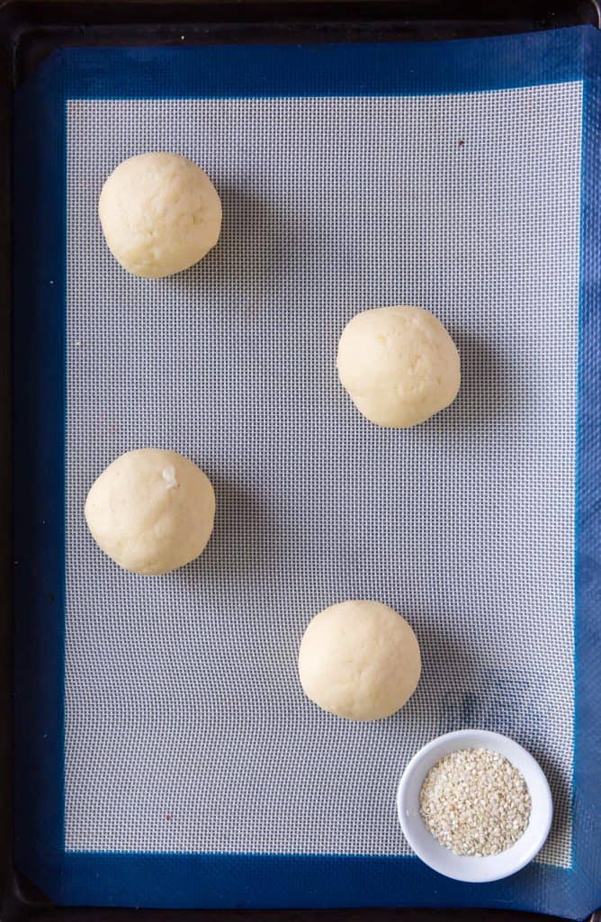 rolled hamburger buns on a baking sheet