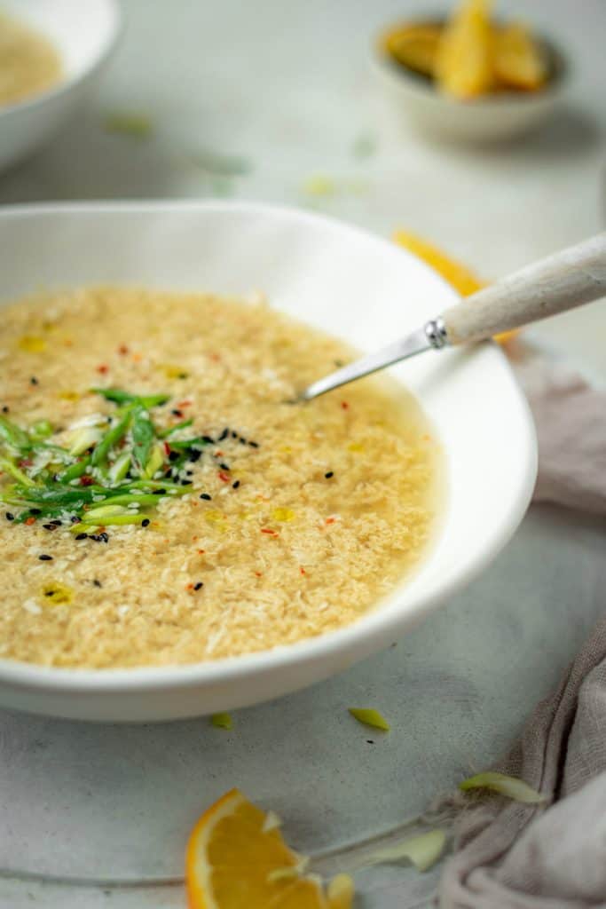 A modern white ceramic bowl with freshly made egg drop soup