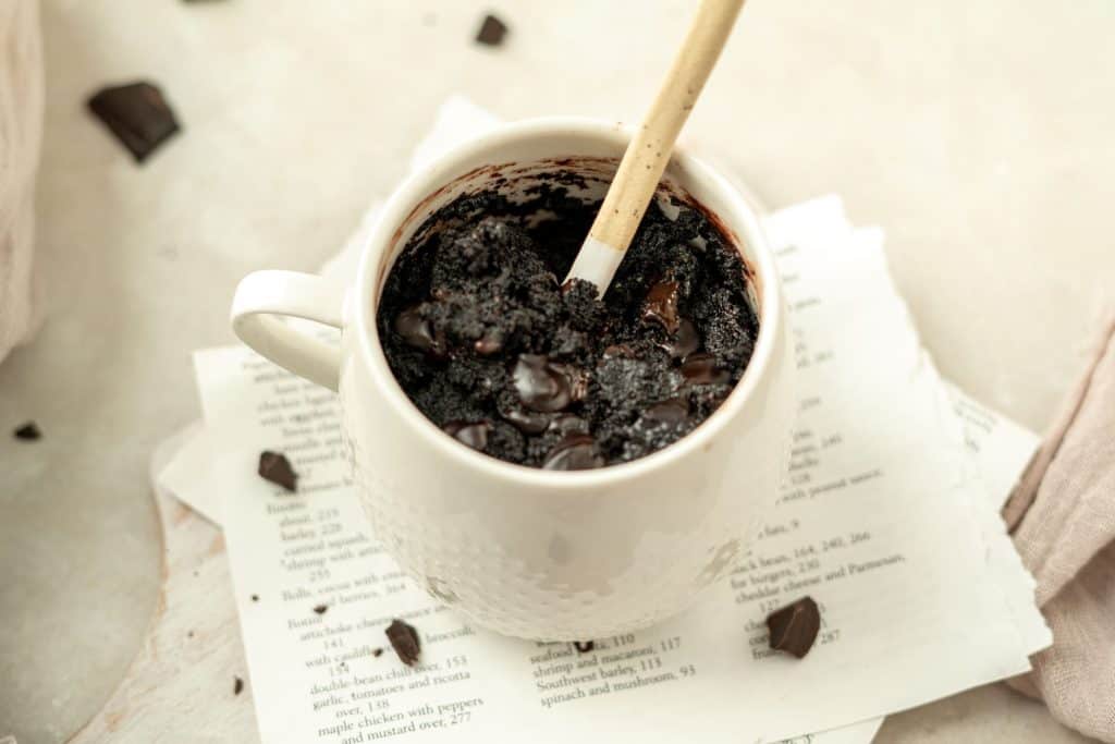 Keto Mug Brownie dark chocolate chunks on a black cocoa powdered brownie