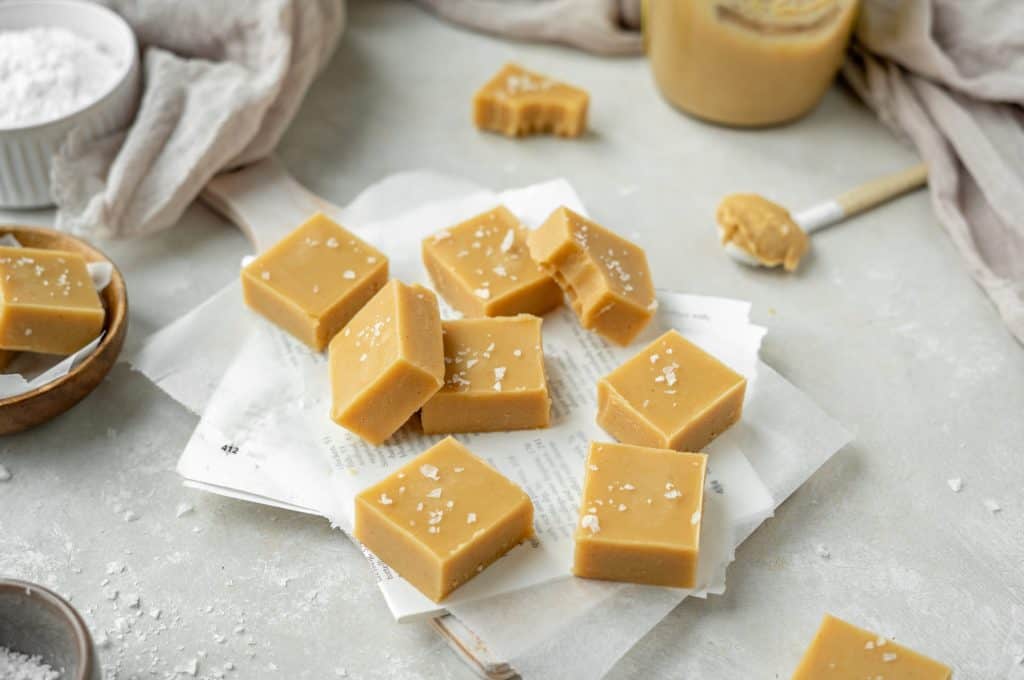 keto peanut butter fudge Thick slices of peanut butter fudge sprinkled and surrounded by salt flakes