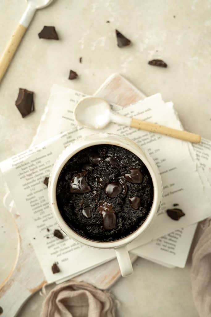 Keto Mug Brownie a white mug with some keto brownie inside. It's sitting on a folded newspaper