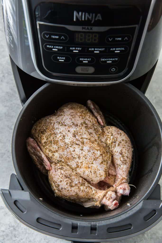 Whole chicken in a round black air fryer